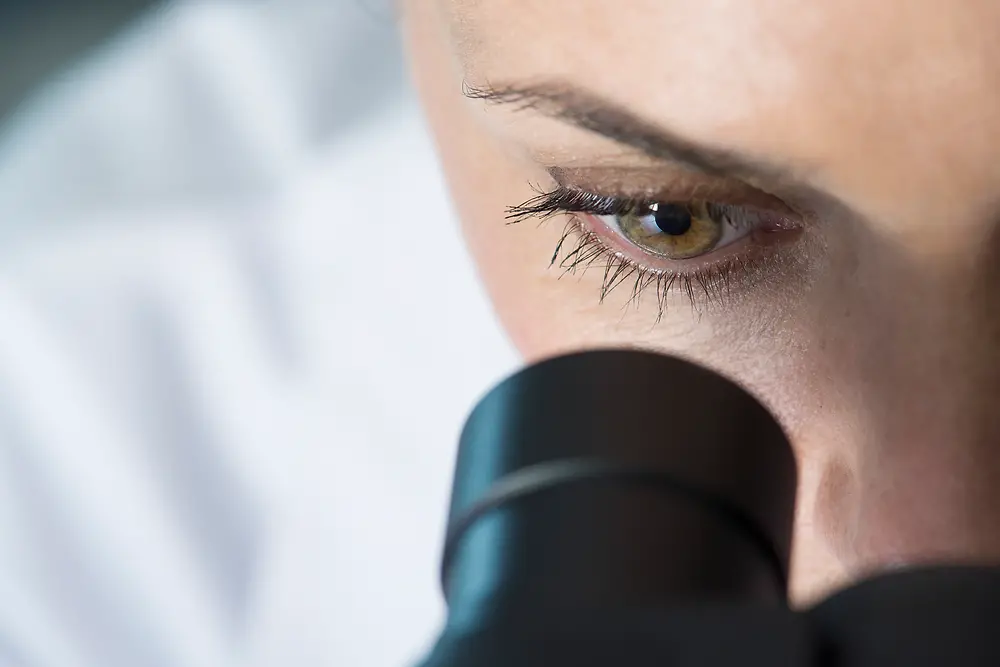 Naisen silmä katsoo mikroskooppiin